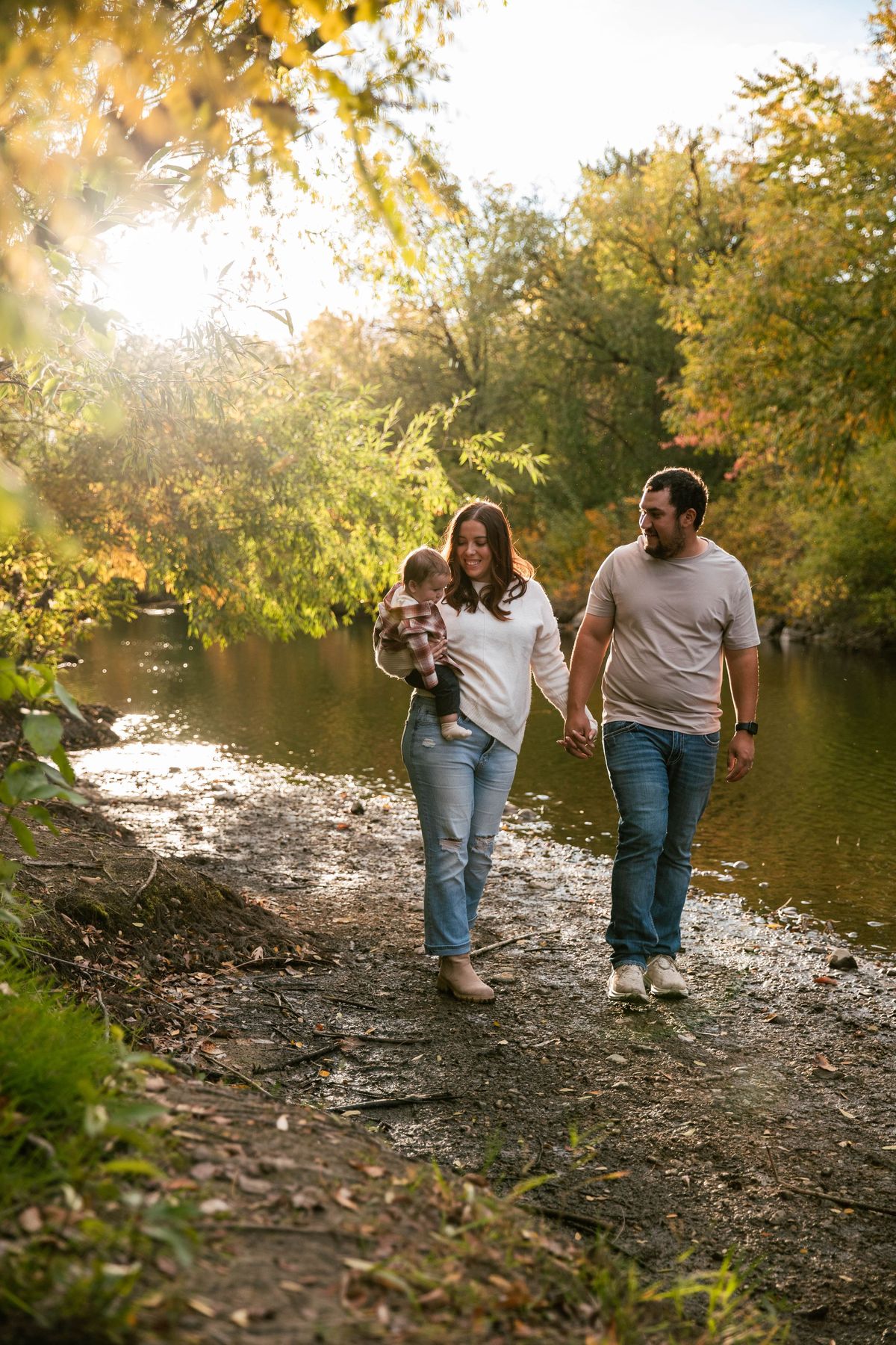 A family walking beside the river in golden autumn light